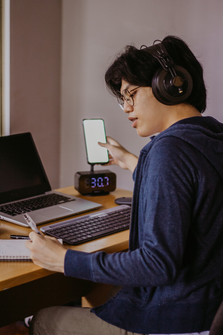 Male Student in Headphones Studying at the Table with Gadgets